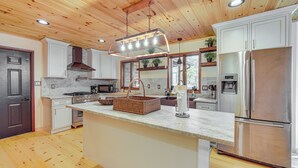 A modern kitchen with wooden ceiling, stainless steel appliances, and a large island. - Ski, Hike & More: Spacious Log Cabin in Long Pond (Pocono Summit)