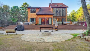 A modern two-story house with a stone patio, outdoor seating, and a fire pit. - Ski, Hike & More: Spacious Log Cabin in Long Pond (Pocono Summit)