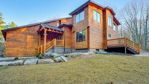 A log cabin with a wooden exterior, a covered porch, and a staircase leading to a deck. - Ski, Hike & More: Spacious Log Cabin in Long Pond (Pocono Summit)
