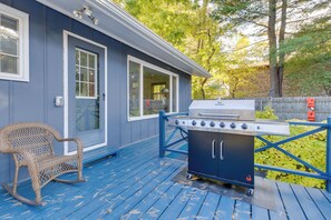 Eine blaue Terrasse mit Grill und einem Korbstuhl.
