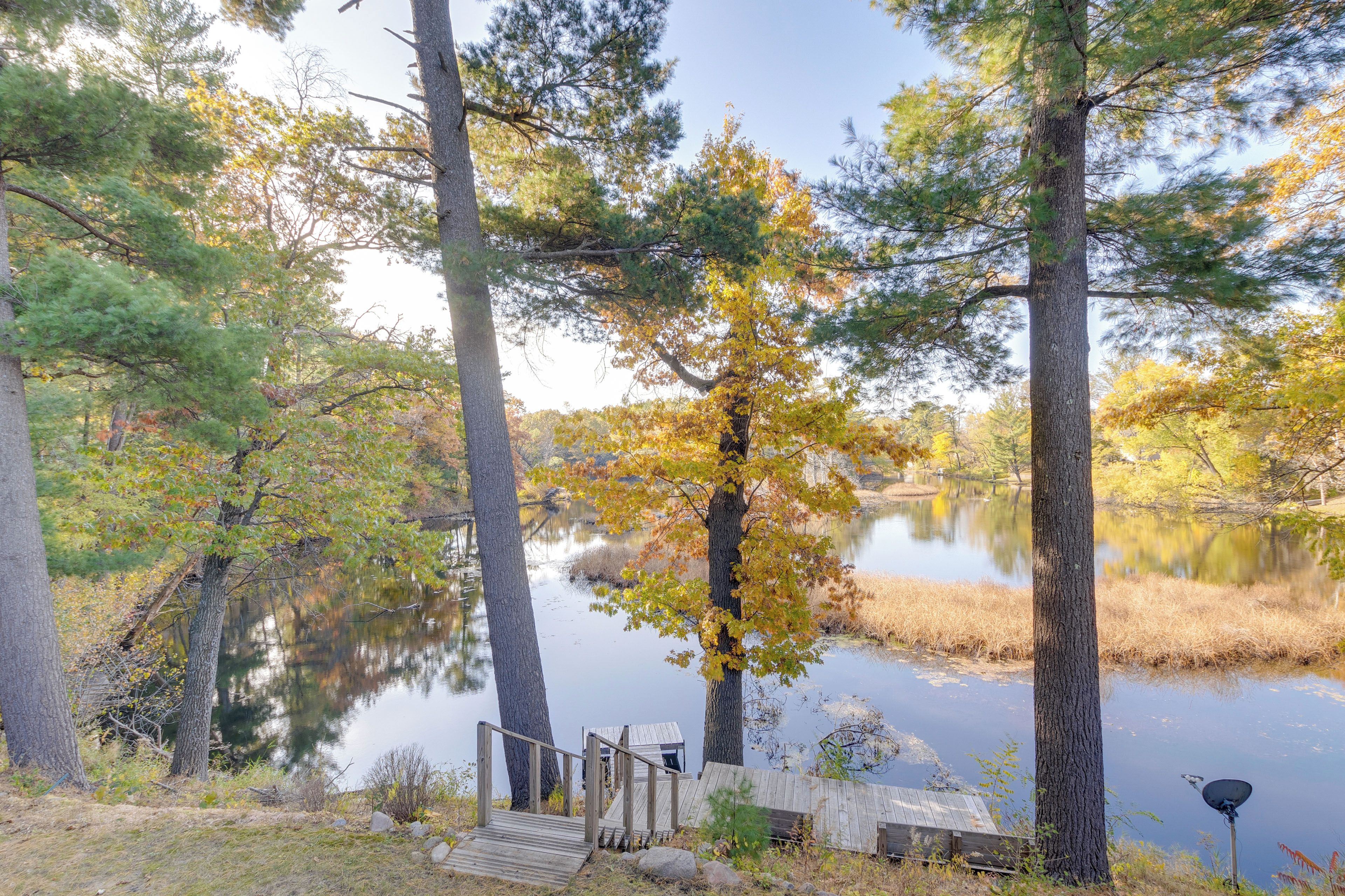 A tranquil lakeside setting with a wooden dock and a small cabin-like structure.