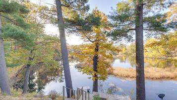 A tranquil lakeside setting with a wooden dock and a small cabin-like structure.
