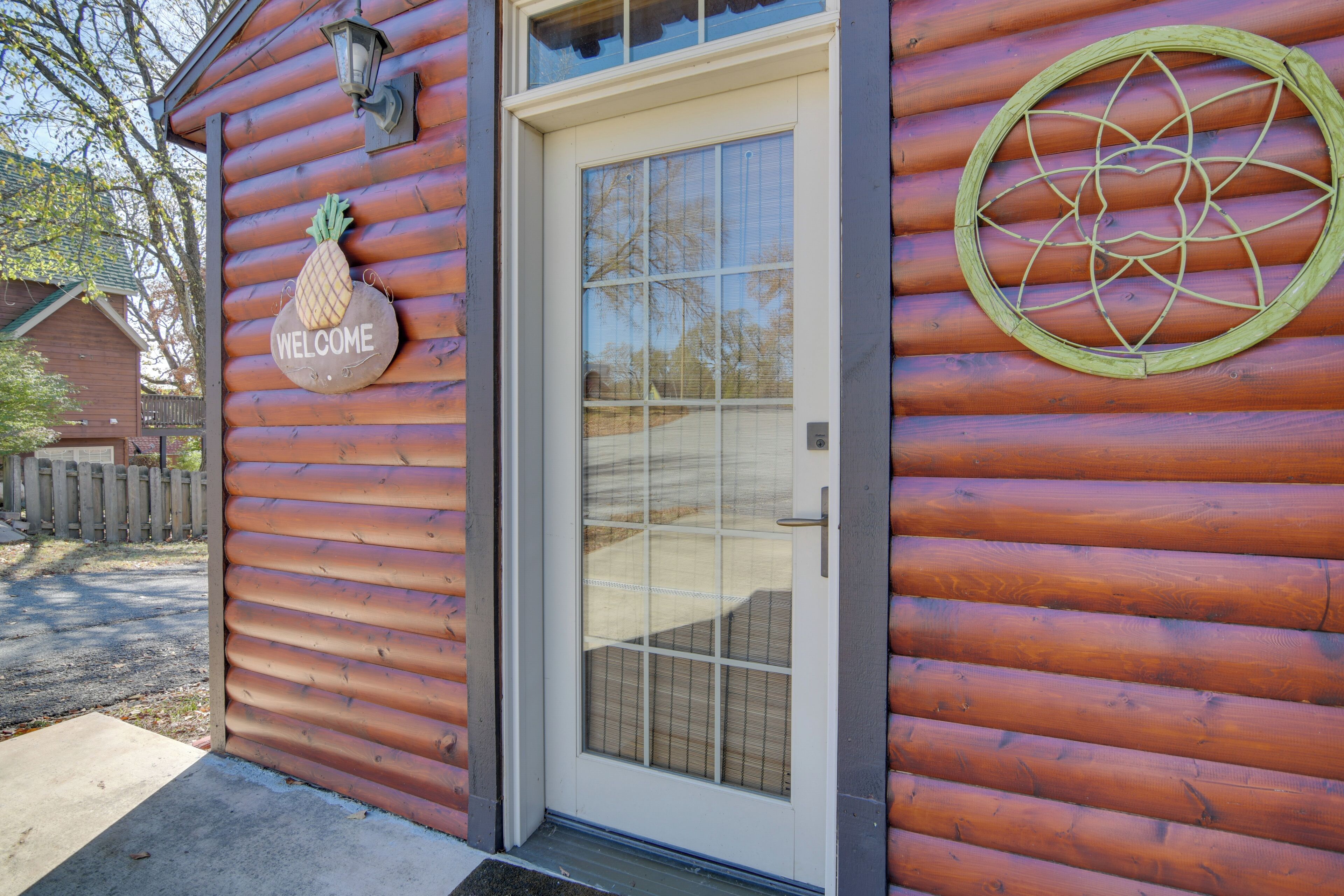 A wooden cabin with a white door, a welcome sign, and a circular window design.