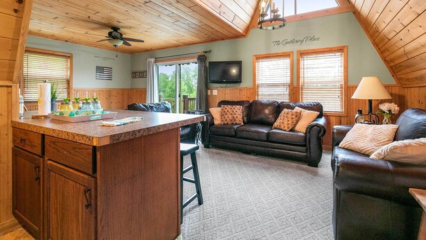 Un interior de cabaña acogedor, con una zona de cocina, una sala de estar con sofá de cuero y un comedor.