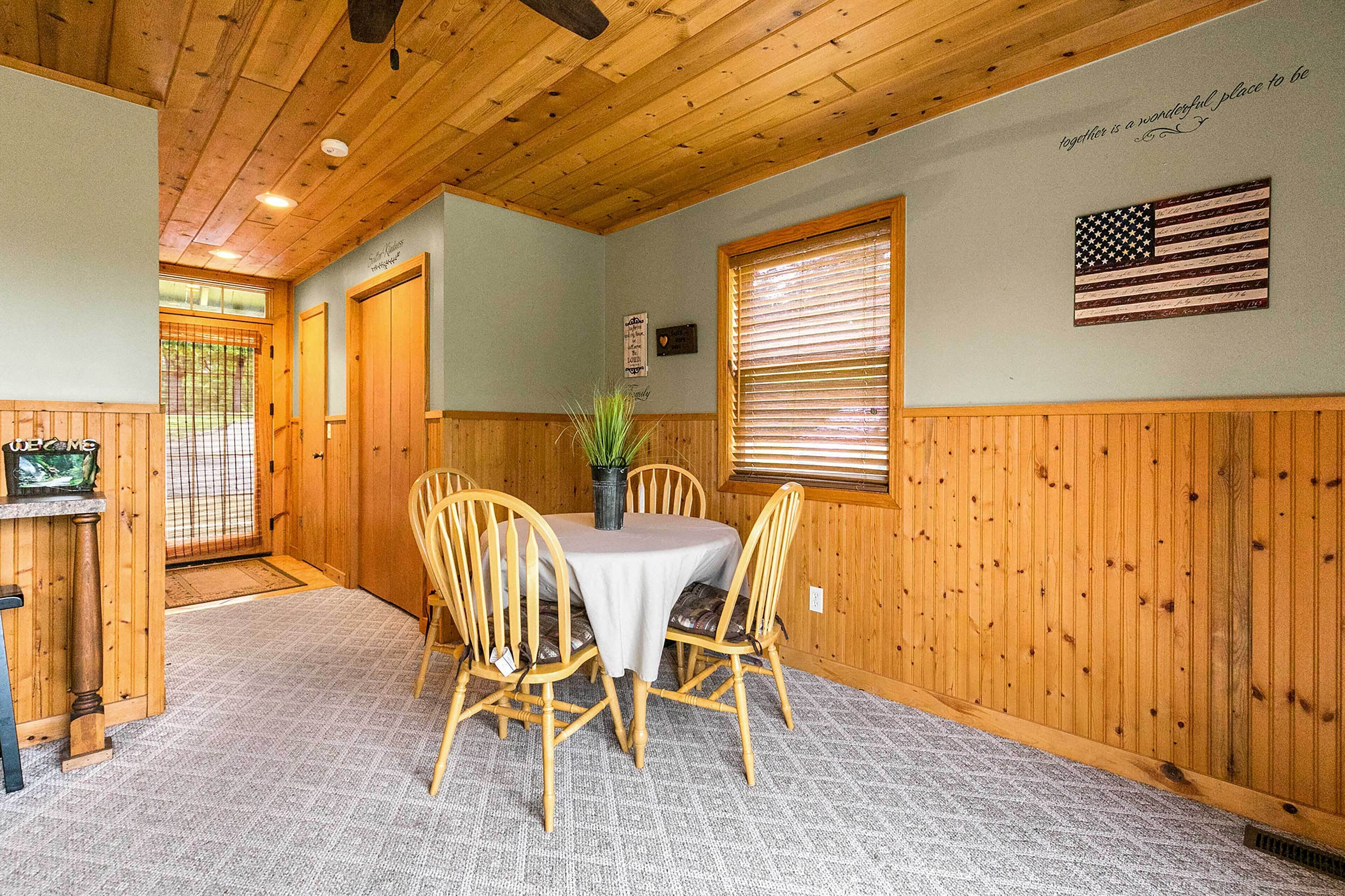 Un coin repas avec une table et des chaises en bois, une plante en pot et un drapeau américain accroché au mur.