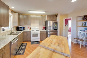 Una cocina con gabinetes de madera, electrodomésticos de acero inoxidable, una mesa de comedor de madera y una isla de cocina.