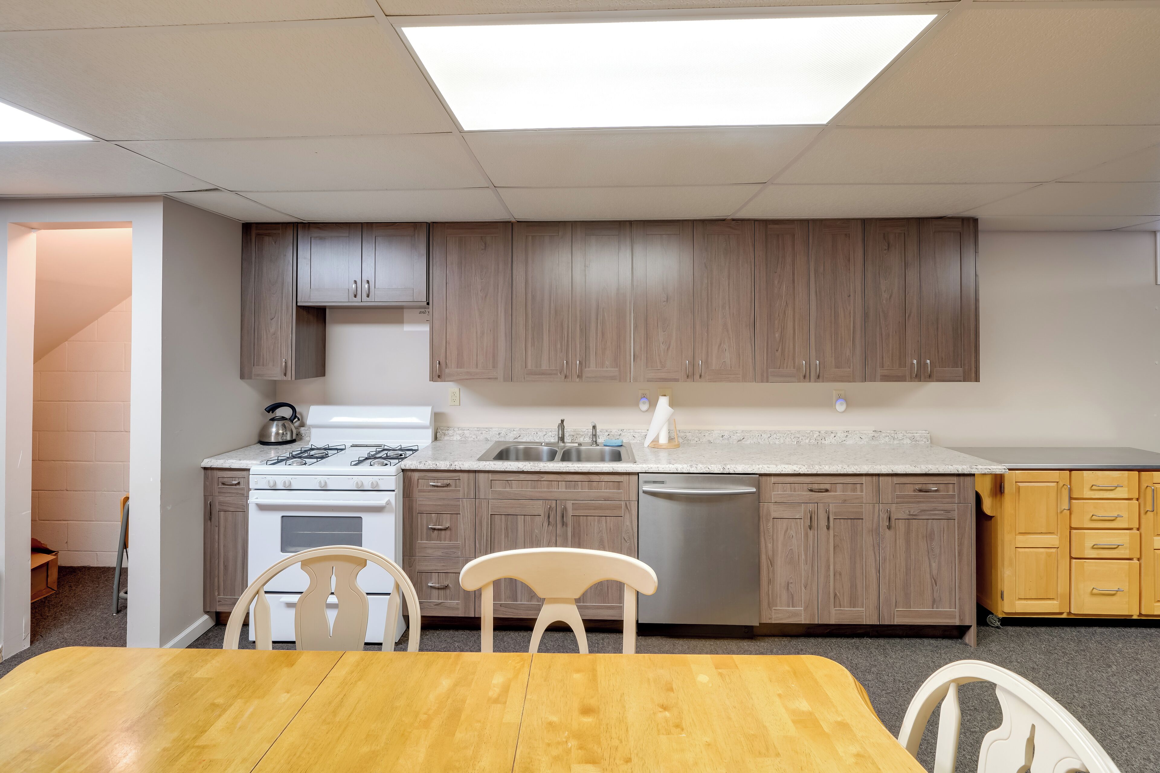 Une cuisine avec des meubles de rangement en bois, une cuisinière blanche et un évier.