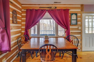 Una habitación con paneles de madera, una mesa de comedor, sillas y cortinas.