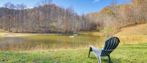 A lakeside bench overlooking a calm lake with a forested backdrop.