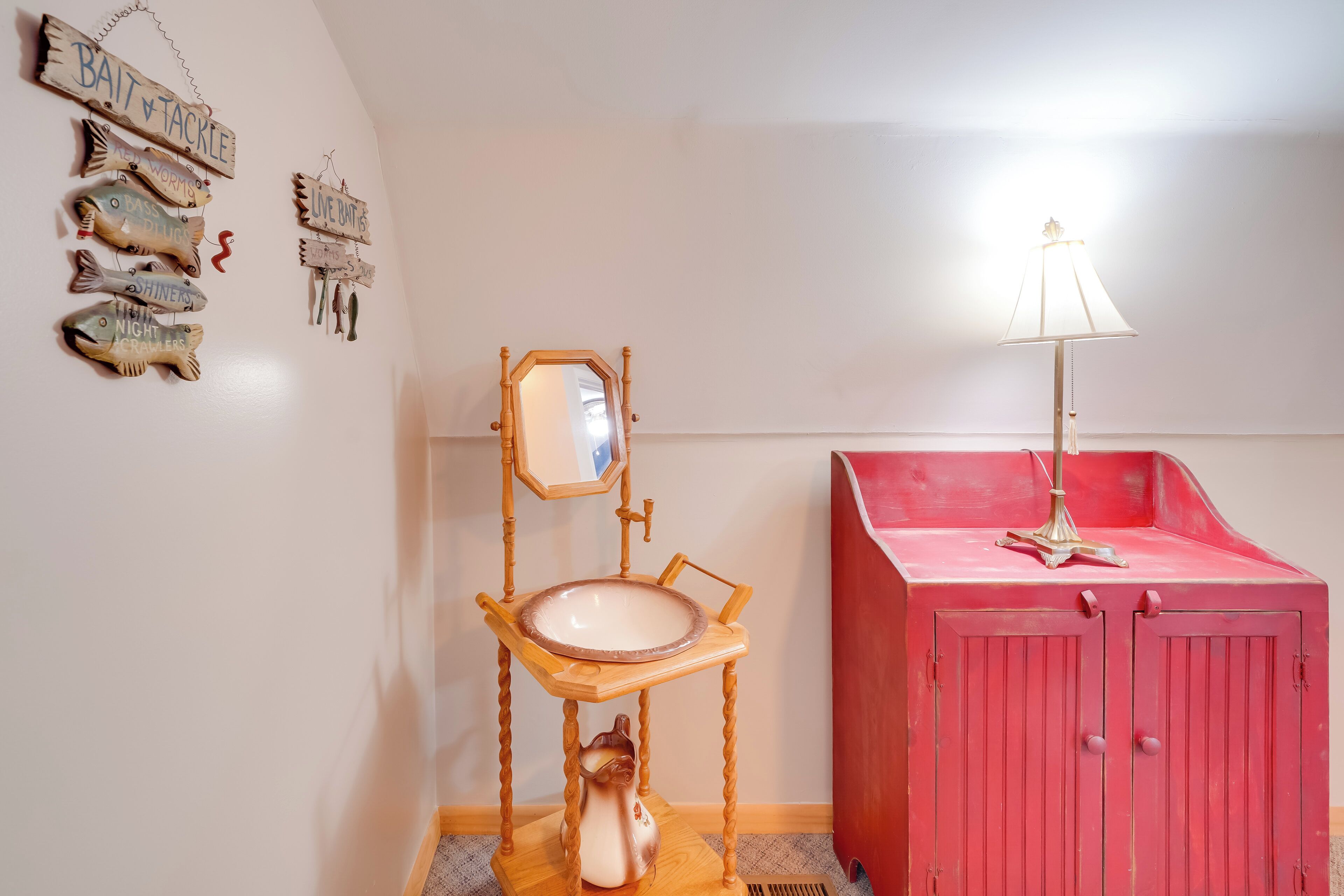 A bathroom with a wooden vanity, a red cabinet, and wall-mounted fish-themed decorations.