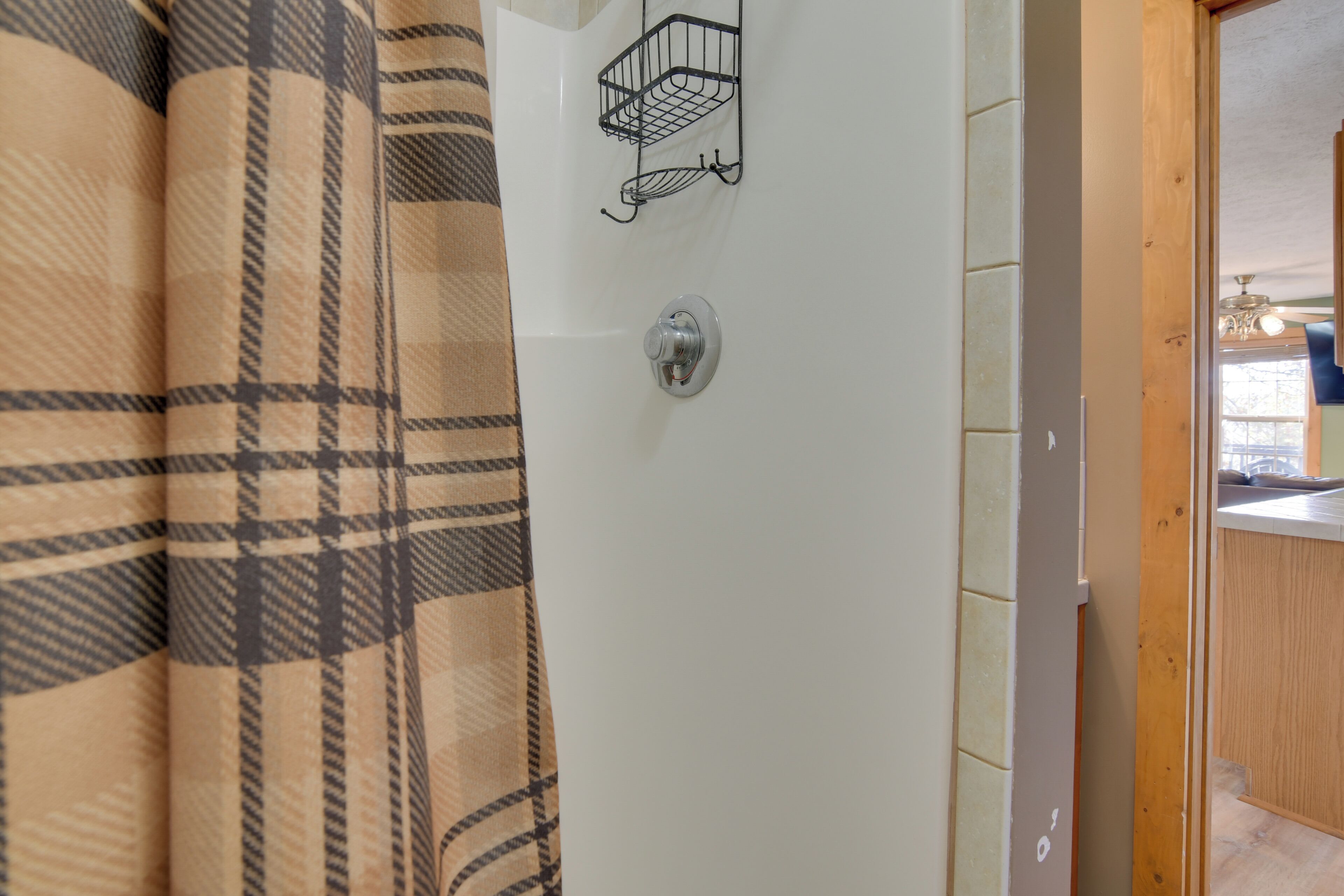 A bathroom with a checkered shower curtain, a towel rack, and a sink with a wooden countertop.