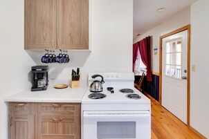 Una cocina con armarios de madera, una estufa blanca y una cafetera.