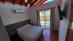 Une chambre dotée d’un lit, d’un ventilateur de plafond, d’un appareil de climatisation et offrant une vue sur l’espace extérieur abritant une piscine.