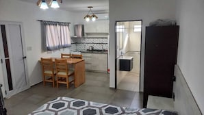 Un espace de vie compact comprenant un coin repas, une kitchenette et une petite salle de bain.