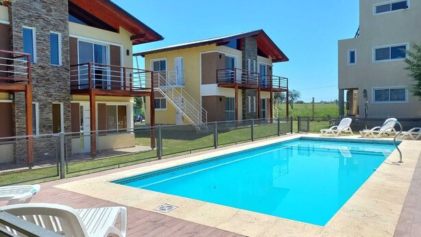 Une piscine rectangulaire dotée d’une terrasse en bois et de chaises longues.