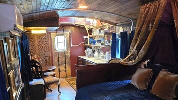 Una camera accogliente in stile baita, con soffitto in legno, un letto con copriletto blu, una sedia rossa, un tavolino e un tappeto decorato.