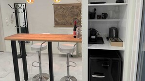 Eine kompakte Küche mit einer Holzauslage, zwei Barhocker, einer Wandkunst mit einer Vintage-Karte und modernen Leuchten.