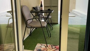 Ein Essbereich mit Tisch und Stühlen, einem Bild an der Wand und Blick ins Freie.