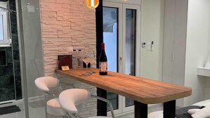 Eine moderne Küche mit Holzbalken, zwei Barhocker und Pendelleuchten.