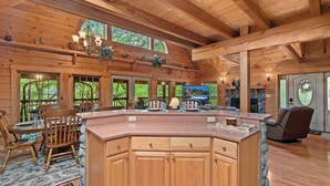 A spacious wooden cabin interior with a large kitchen area, dining table, and seating. - Beautiful Three Bedroom Cabin Directly On Cosby Creek (Cosby)