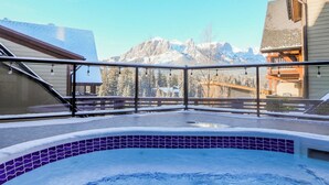 Área de hidromassagem com vista para montanhas cobertas de neve.