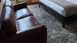 Quarto com cama, ventilador de teto, janela grande e vista para montanhas.
