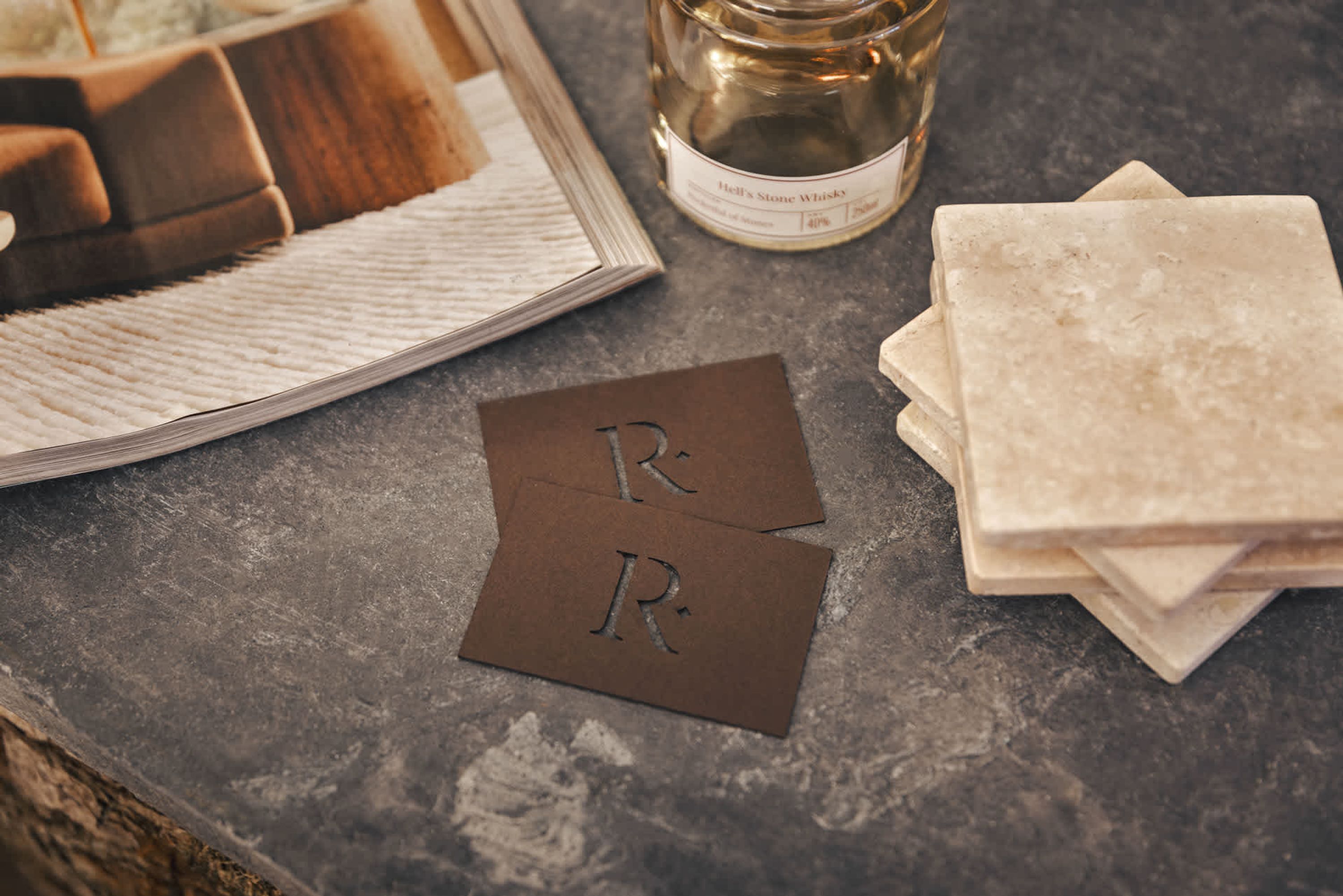 A table with a framed picture, a bottle of Hell's Stone Whisky, and two nameplates with initials.