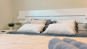 A neatly made bed with a grey blanket and two pillows, a bedside table with a plant, and a modern headboard. - Modern Retreat With Spacious Yard Cozy Interiors (Ontario)