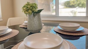A dining table with a vase of green flowers, white plates, and bowls. - Modern Retreat With Spacious Yard Cozy Interiors (Ontario)