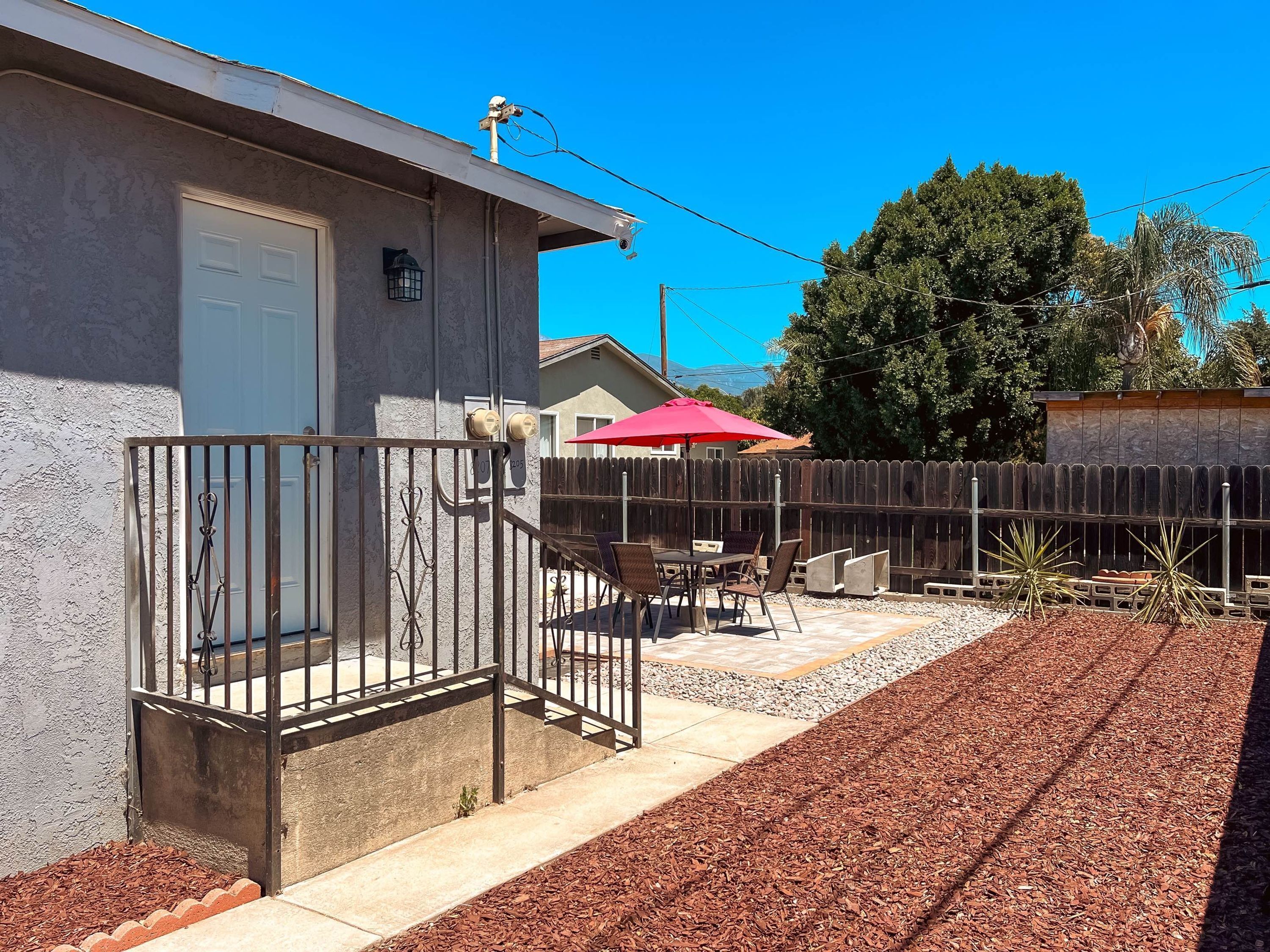 A residential property with a covered patio, outdoor furniture, and a fenced yard.