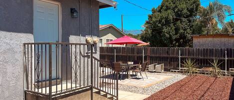 A residential property with a covered patio, outdoor furniture, and a fenced yard.