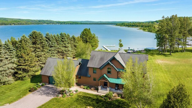 A lodge with a large lake view, a dock, and a well-maintained lawn.