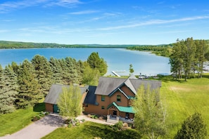 A lodge with a large lake view, a dock, and a well-maintained lawn.