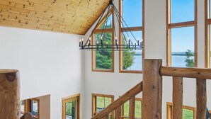 A wooden staircase with large windows overlooking a lake.