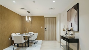 A modern dining area with a wooden accent wall, a large framed artwork, and a black console table. - 2BR w Canal & Burj View Near Dubai Mall (Dubai)