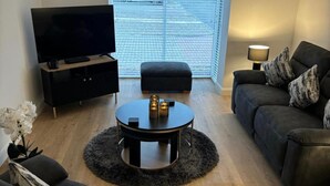 A living room with a flat-screen TV, a round coffee table with candles, a sofa, and a lamp. - 2 Bedroom, Cozy Coastal Retreat in Anstruther (Anstruther)