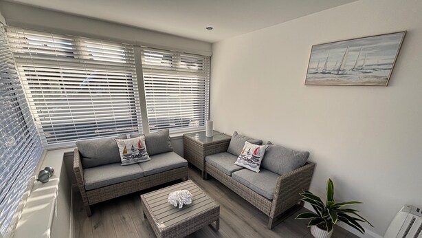 A modern living room with grey sofas, wicker furniture, a wooden coffee table, and a potted plant. - 2 Bedroom, Cozy Coastal Retreat in Anstruther (Anstruther)
