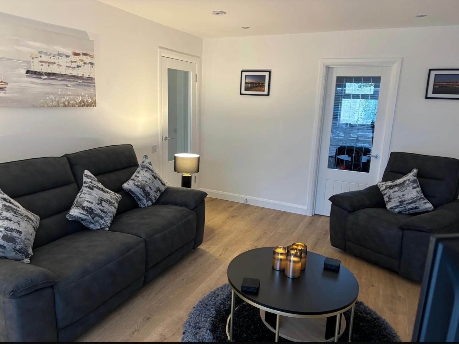 A modern living room with two dark sofas, a round coffee table, and a lamp.
