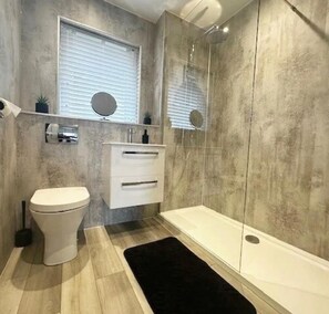 Bathroom features a toilet, vanity with mirror, and bathtub.