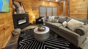 Accogliente interno di una baita in legno con camino, divano e tappeto decorato.