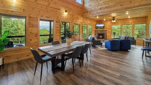 A spacious wooden cabin with a dining area, seating, and a fireplace. - Private Indoor Pool Cabin | Game Room + Firepit (Gatlinburg)