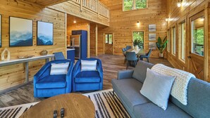 A spacious cabin interior with a loft bedroom, a dining area, and a living room furnished with sofas and chairs. - Private Indoor Pool Cabin | Game Room + Firepit (Gatlinburg)