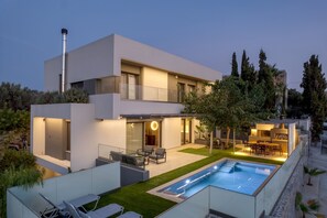 Una casa moderna de dos pisos con piscina, mobiliario exterior y un jardín bien cuidado.