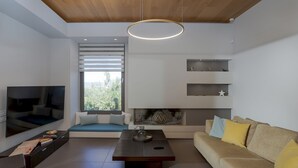 Un salon moderne avec un téléviseur à écran plat, un canapé, une table basse et une cheminée.