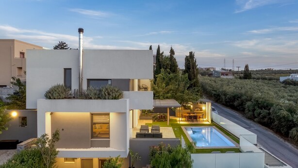Une maison moderne à deux étages, dotée d’une piscine, d’un espace de détente extérieur et d’un jardin bien entretenu.