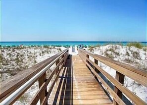 A wooden boardwalk leading to a beach with clear skies.