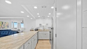 Une cuisine moderne avec des meubles blancs, un plan de travail en marbre et un revêtement de sol en bois.