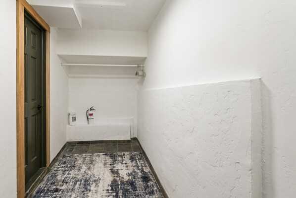 A narrow hallway with a patterned rug, a door, and a white wall with a shelf. - 770 Potato Patch 4 Bedroom Townhouse (Vail)