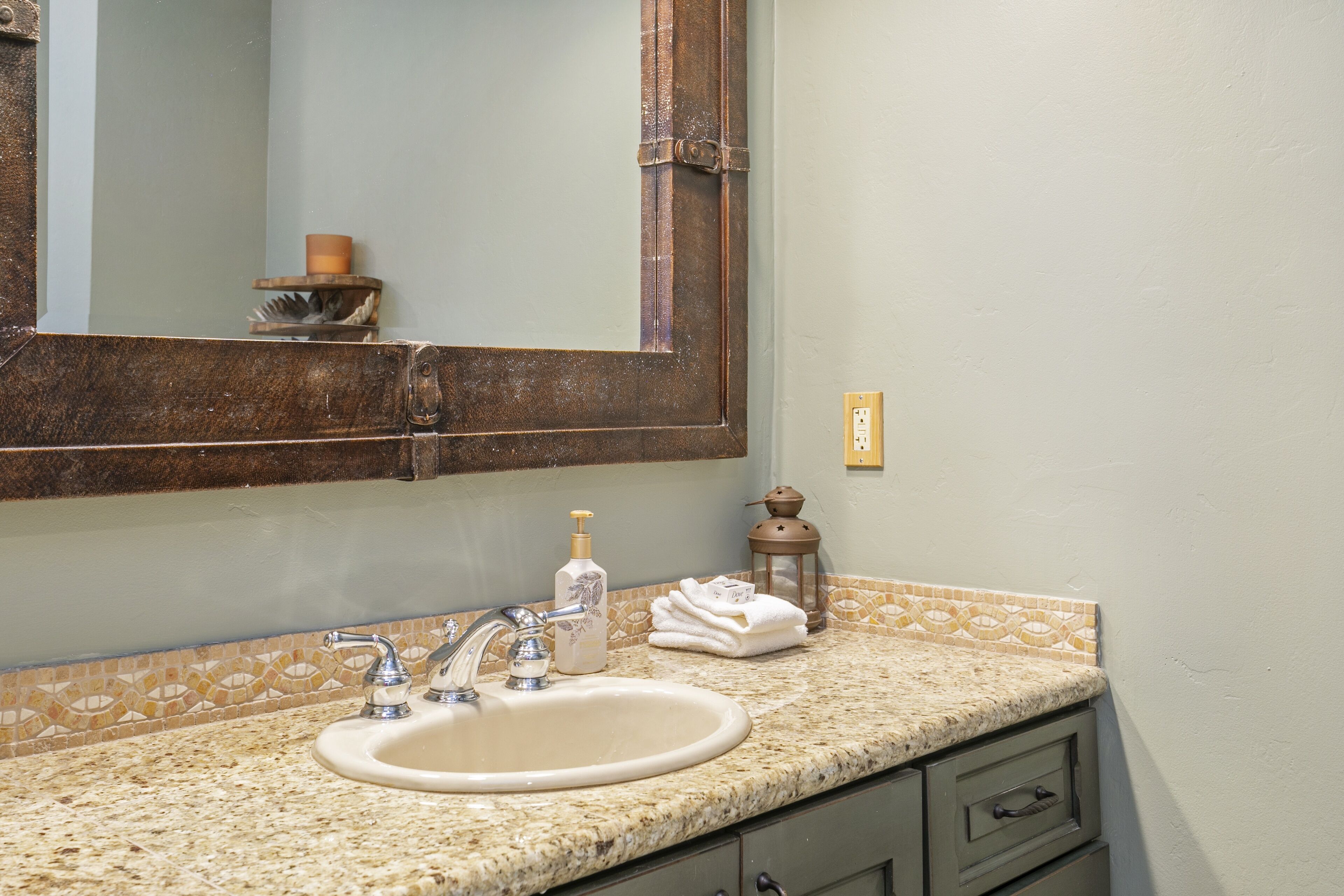 A bathroom with a sink, mirror, and a decorative lantern.