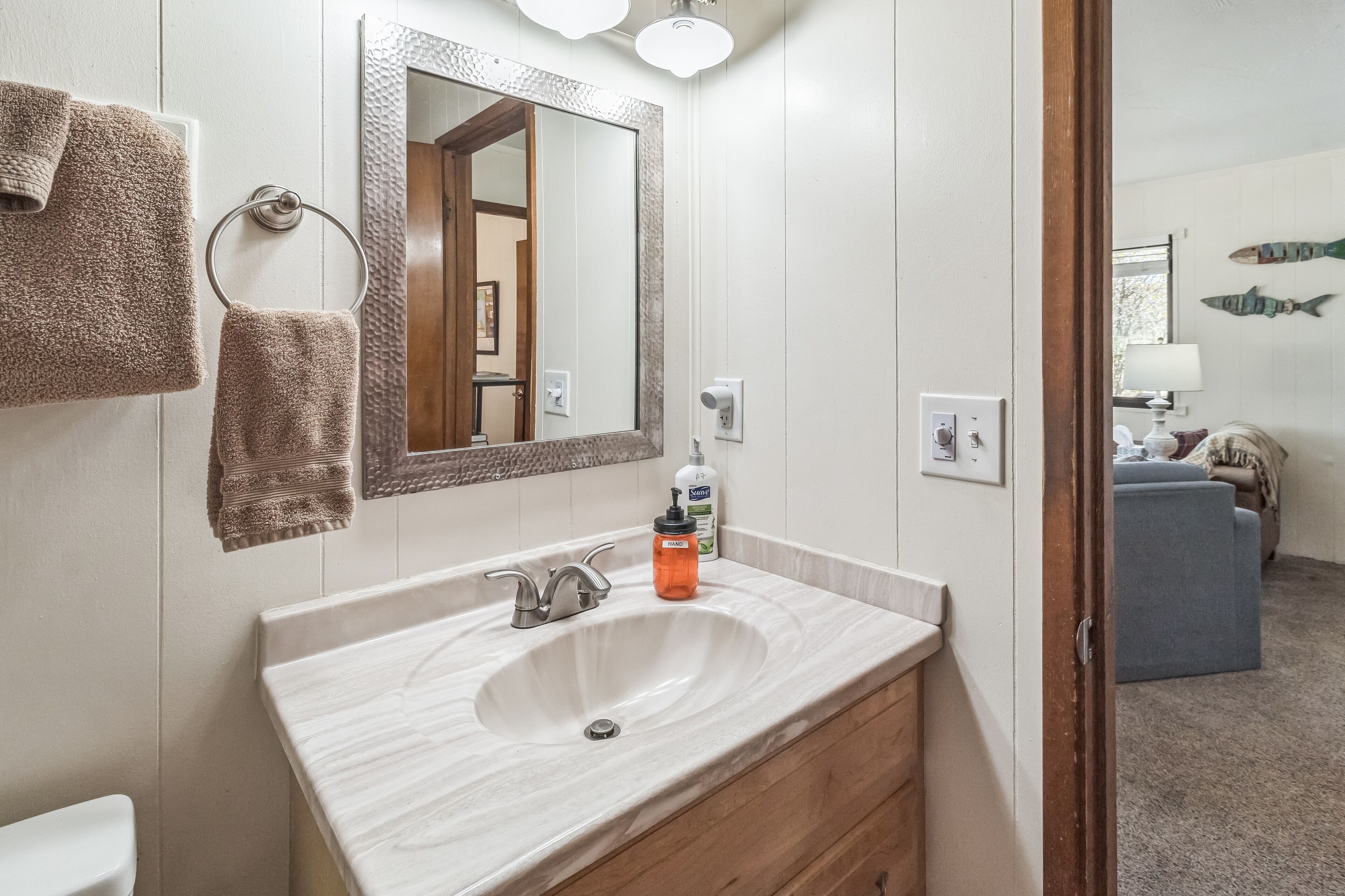 Une salle de bain avec un lavabo en marbre, un miroir et deux serviettes accrochées au mur.